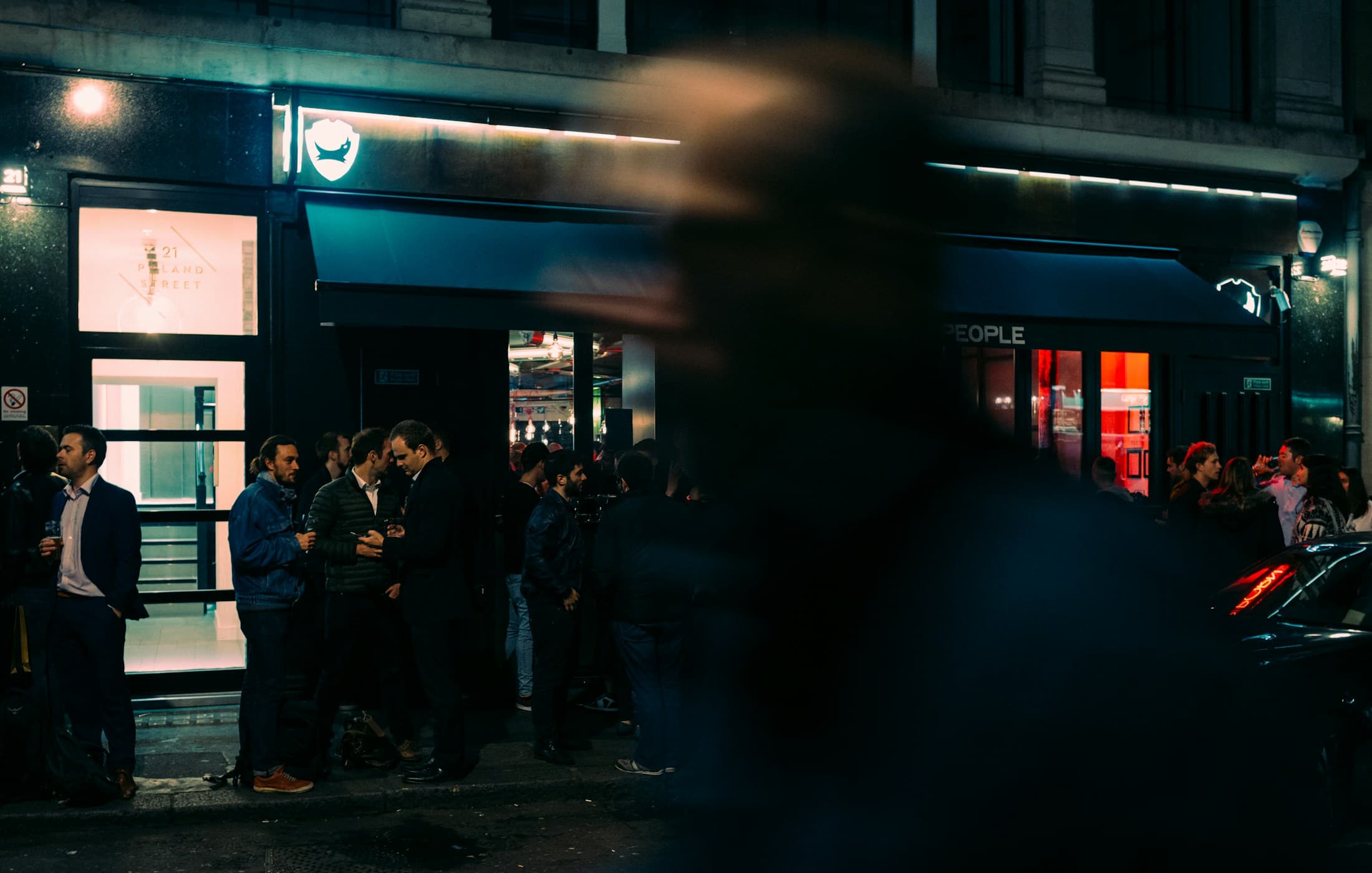 People standing outside a venue in Soho at night