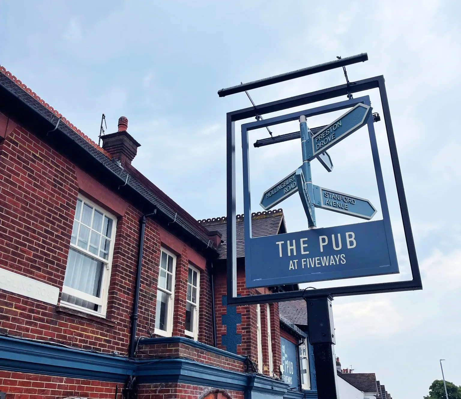 Blue hanging sign for The Pub at Fiveways in Brighton